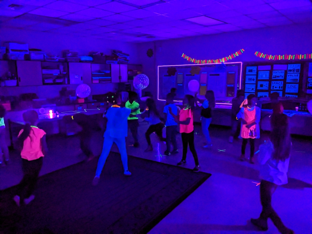 students dancing and playing under black lights