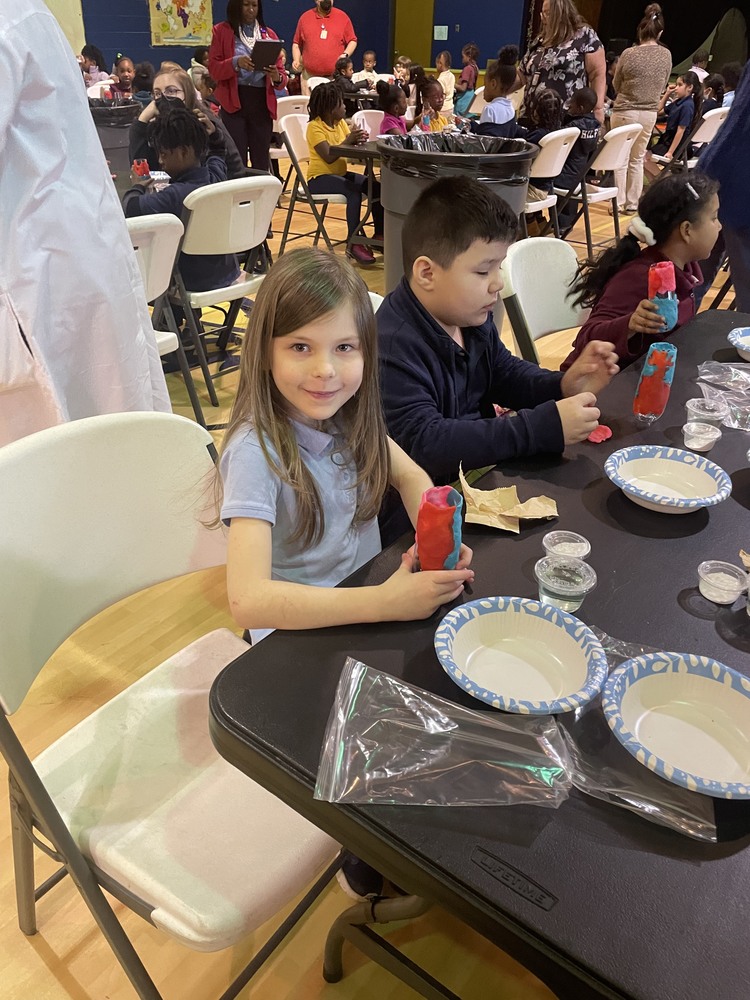 girl and boy sitting at table with science experiment