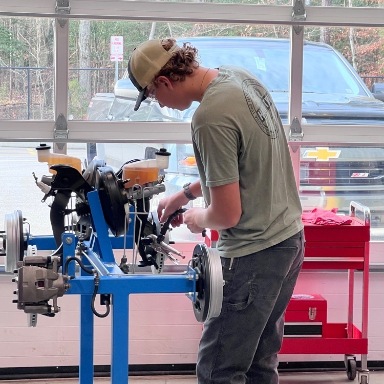 Picture of a young man working on a machine in the automotive shop