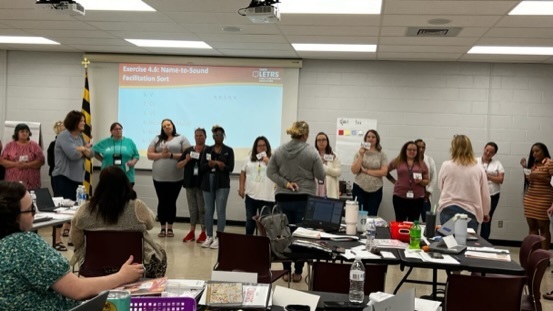 photo of 20+ teachers in a line in a conference room at a training
