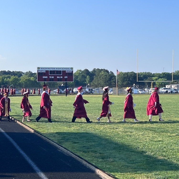 students walking onto the track in cap and gown